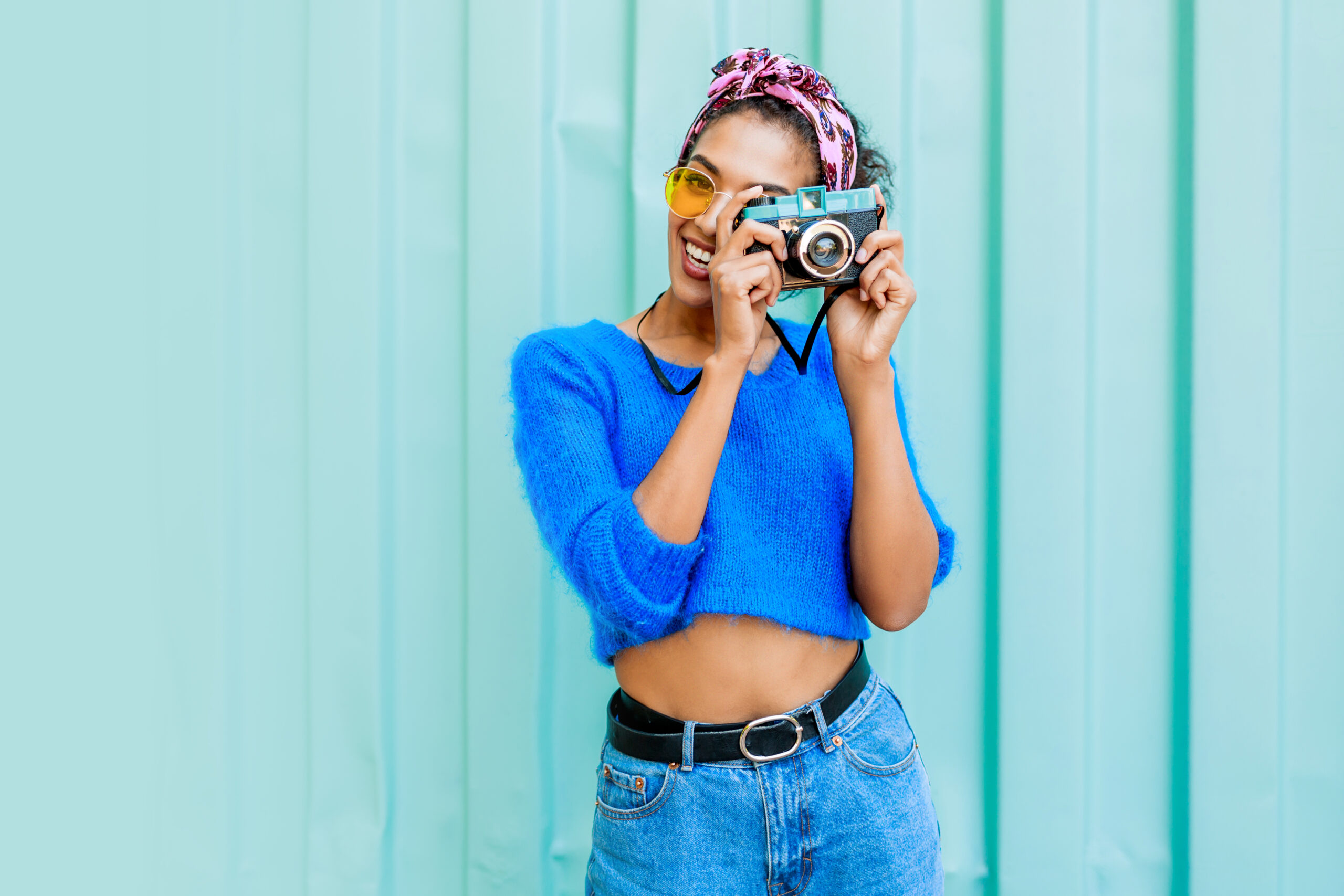 Laughing black girl with cute hairstyle holding retro camera Cohort members working together